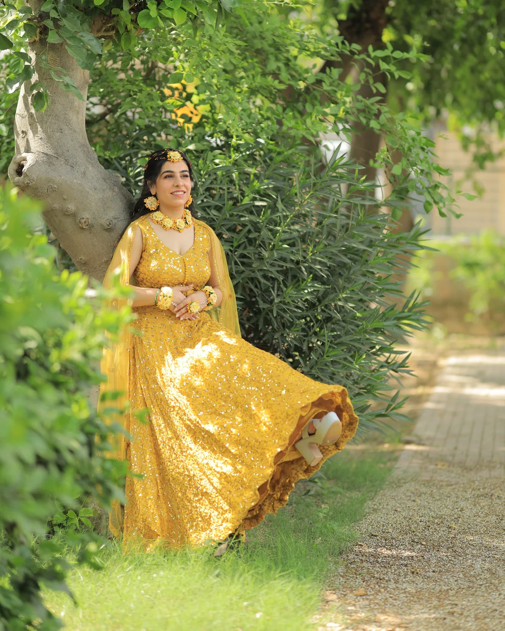 Bride twirling in a yellow lehenga on a garden path