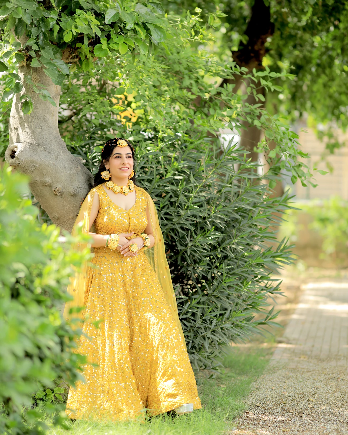 Bride in a yellow lehenga in a sunlit garden