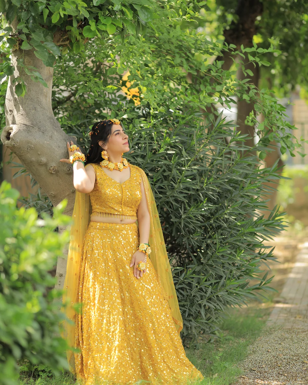 Bride in yellow smiling and adjusting her earring in a garden