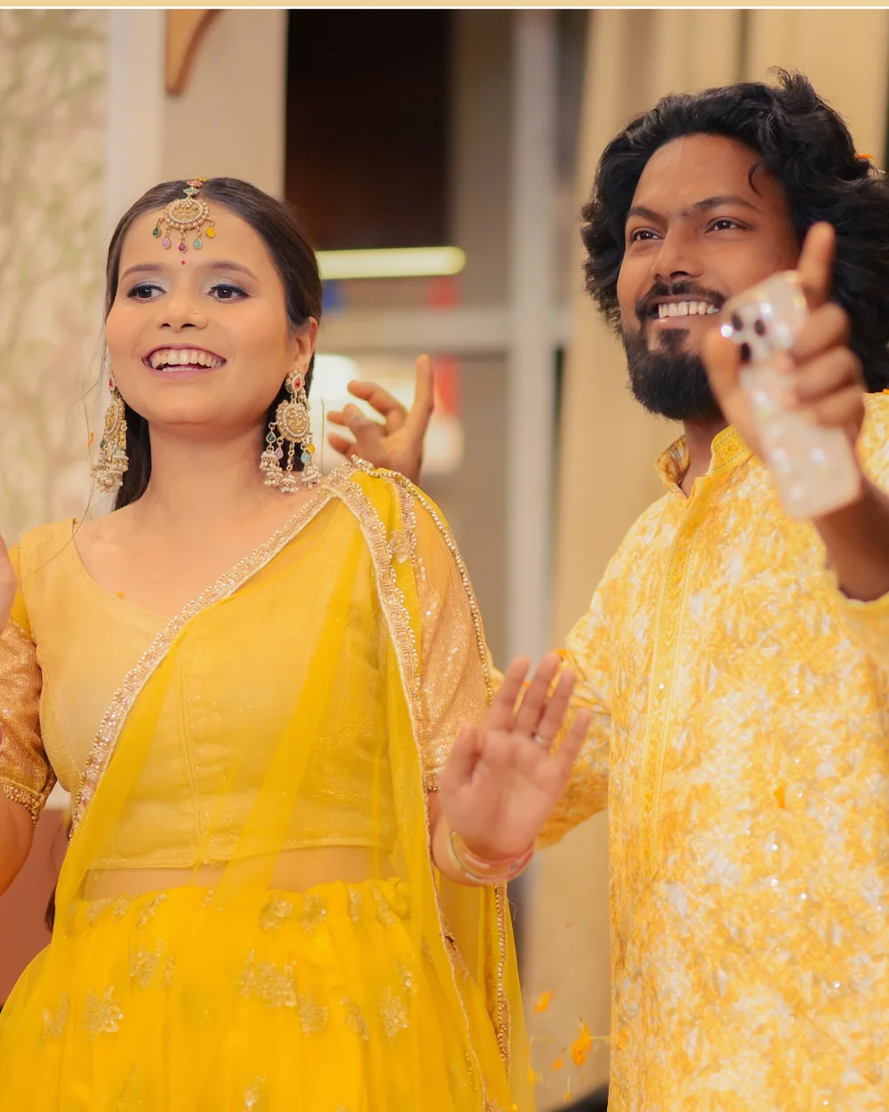 Bride and groom in yellow laughing at their haldi