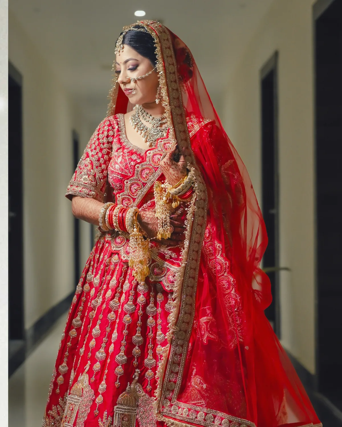 Bride in a red lehenga walking down a palace corridor