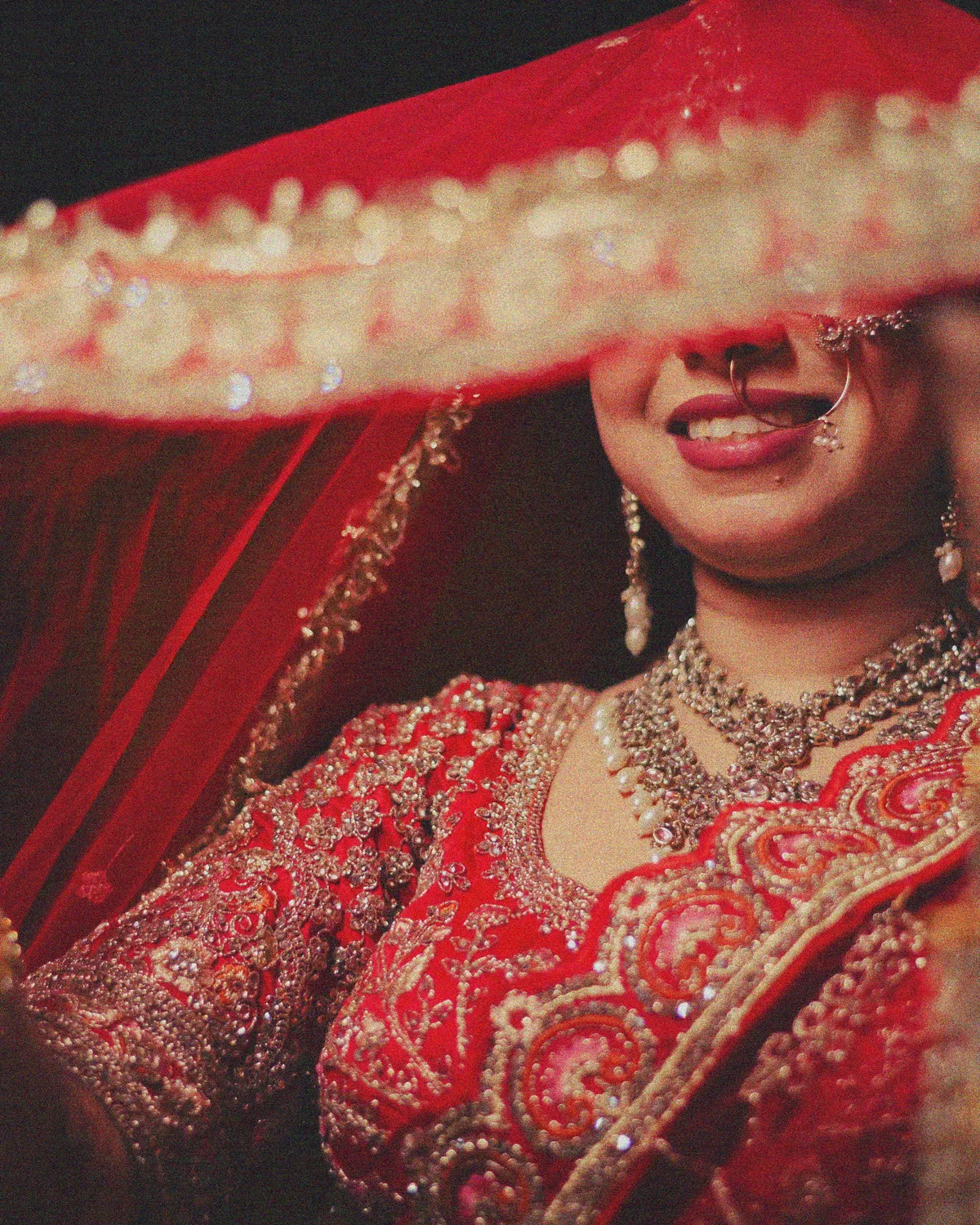 Close-up of a smiling bride lifting her embroidered dupatta