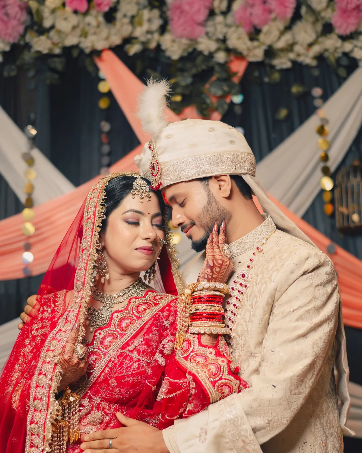 Groom in an ivory sherwani holding his bride close at the mandap